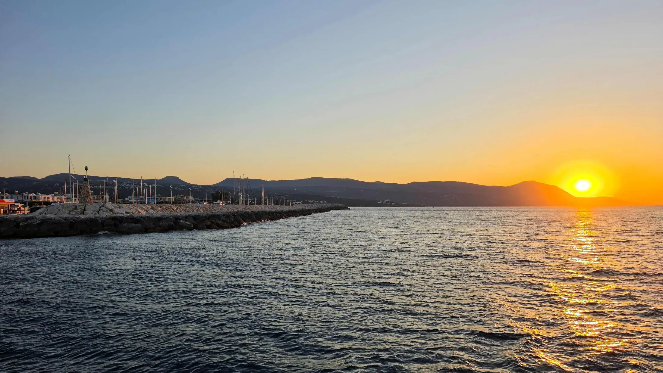 The sun setting over the sea beyond Latchi harbour