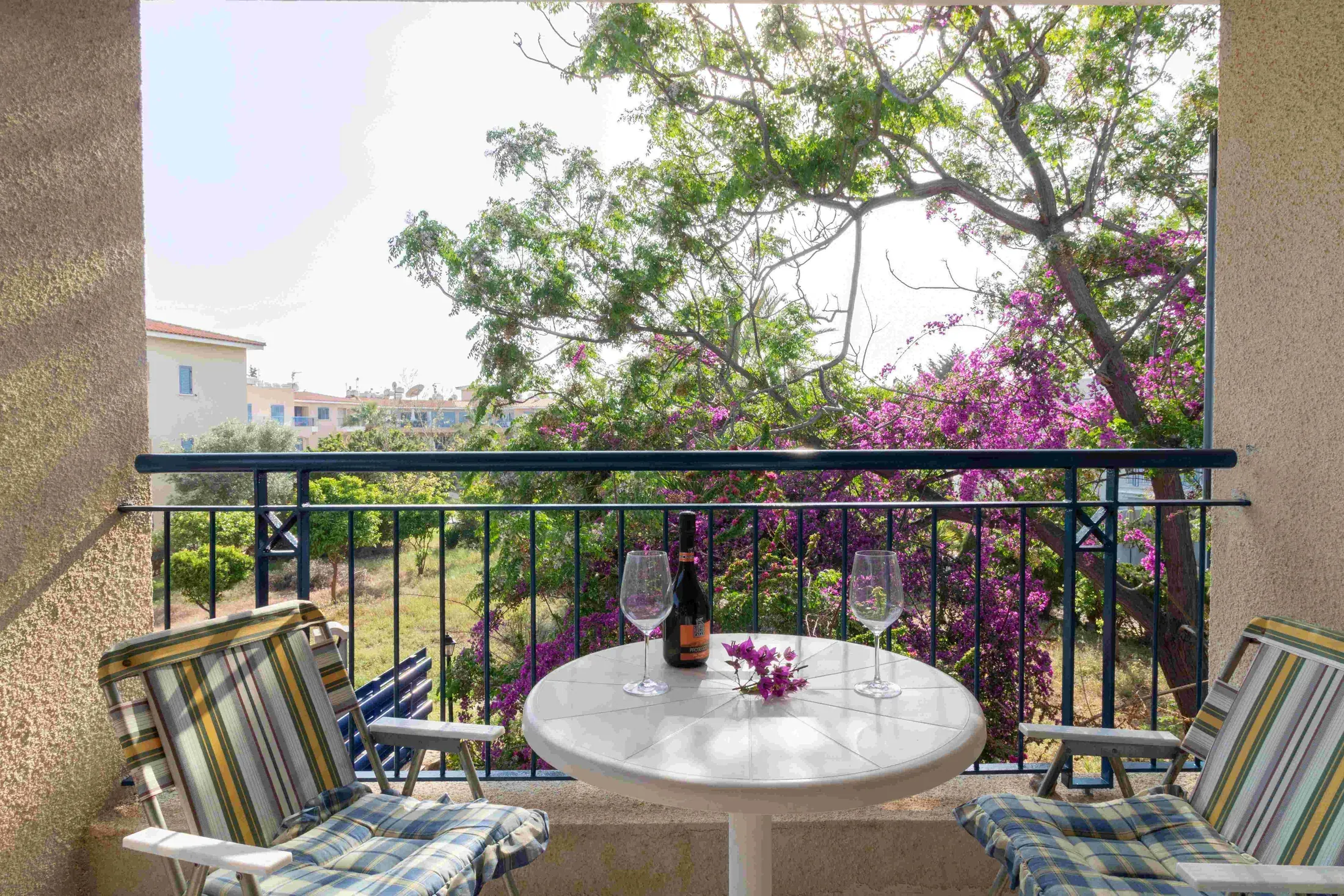 The bedroom balcony with a table for two and bougainvillea over the railing