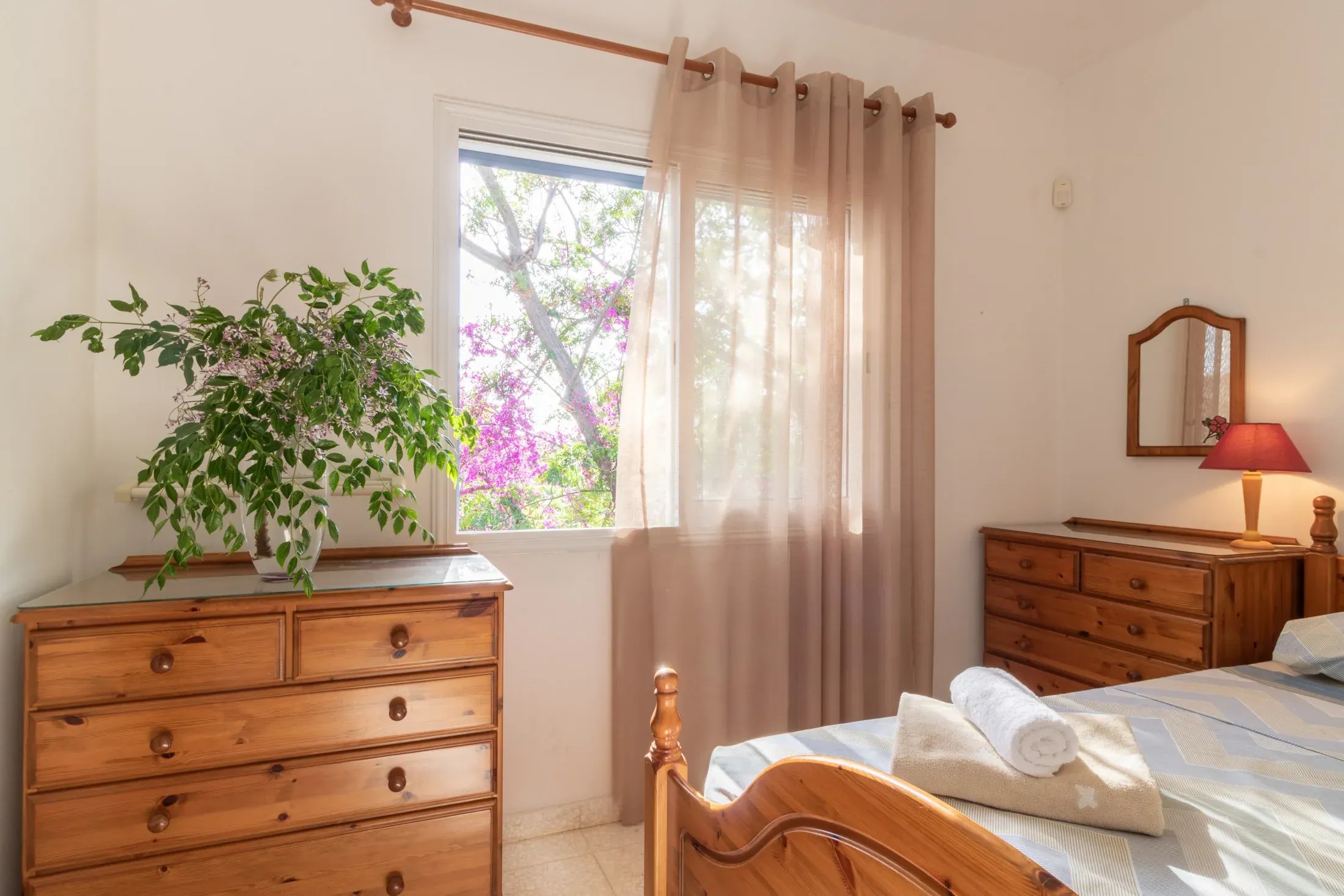 A pine chest of drawers and the bougainvillea through the window