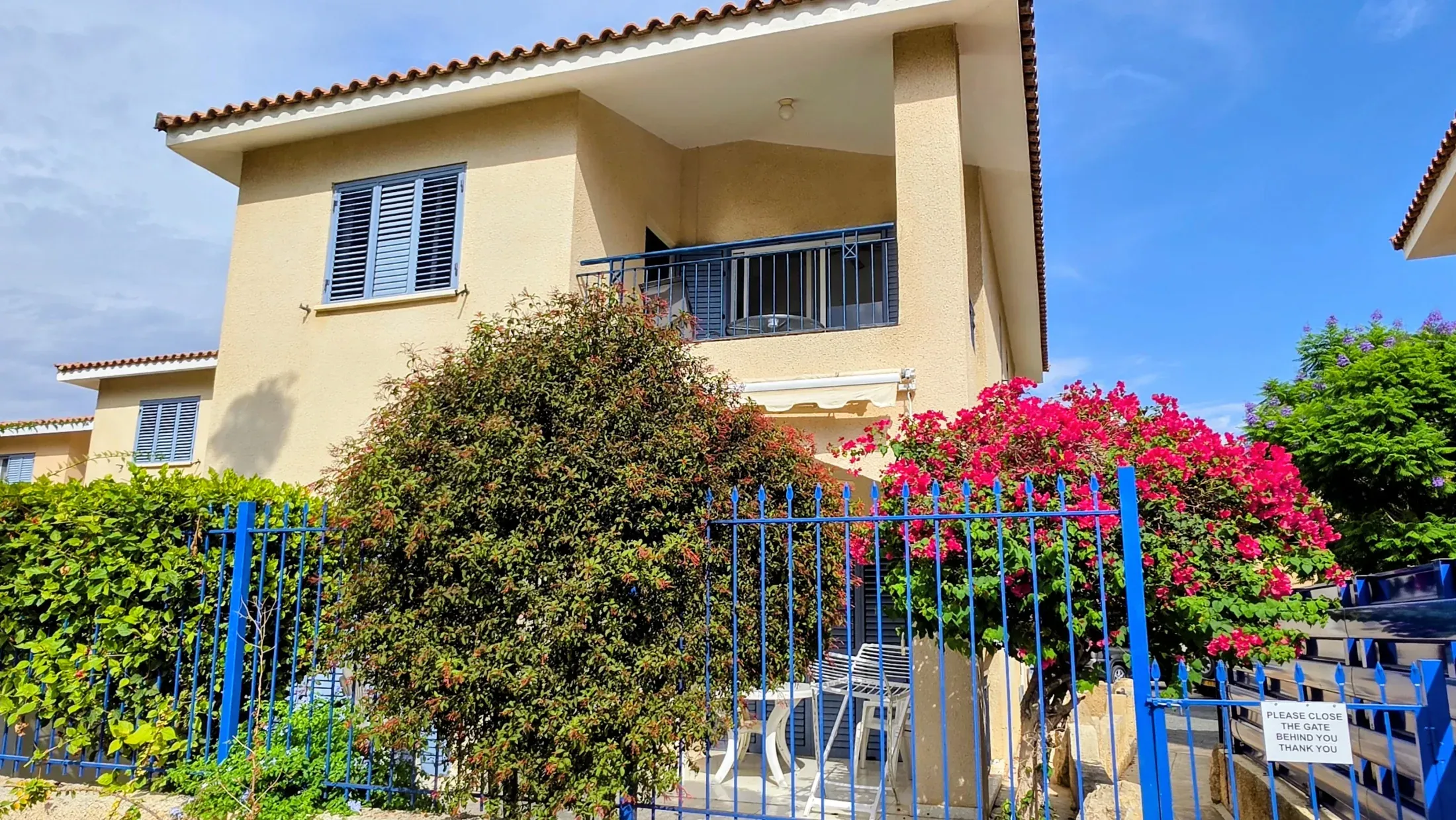 Villa Nadezda seen from the street, bougainvillea in flower over the blue railings, Kato Paphos
